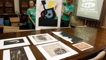 Dos membres de l'Assemblea amb el Miró. A la taula en primer pla les quatre obres de Barceló, a la dreta la de Maria del Mar Bonet feta amb argila i just a dalt una aportació de Pere Jaume. 