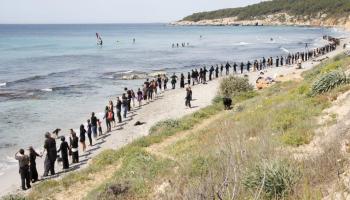 Cadena humana negra damunt l'arena blanca de la platja de Binigaus, a Menorca.