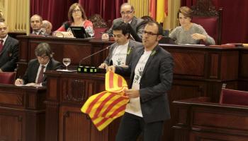 Biel Barceló, líder de MÉS, estén una senyera durant una sessió parlamentària. 