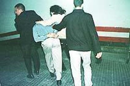 Un dels detinguts és conduït per la Policia a l'interrogatori.